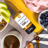 Manuka Doctor Manuka Honey 100 MGO on a table with fruit and tea.